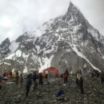 Trekkers tents at Concordia camp on the Baltoro Glacier with the rock spire of Mitre Peak behind, Karakoram, Pakistan