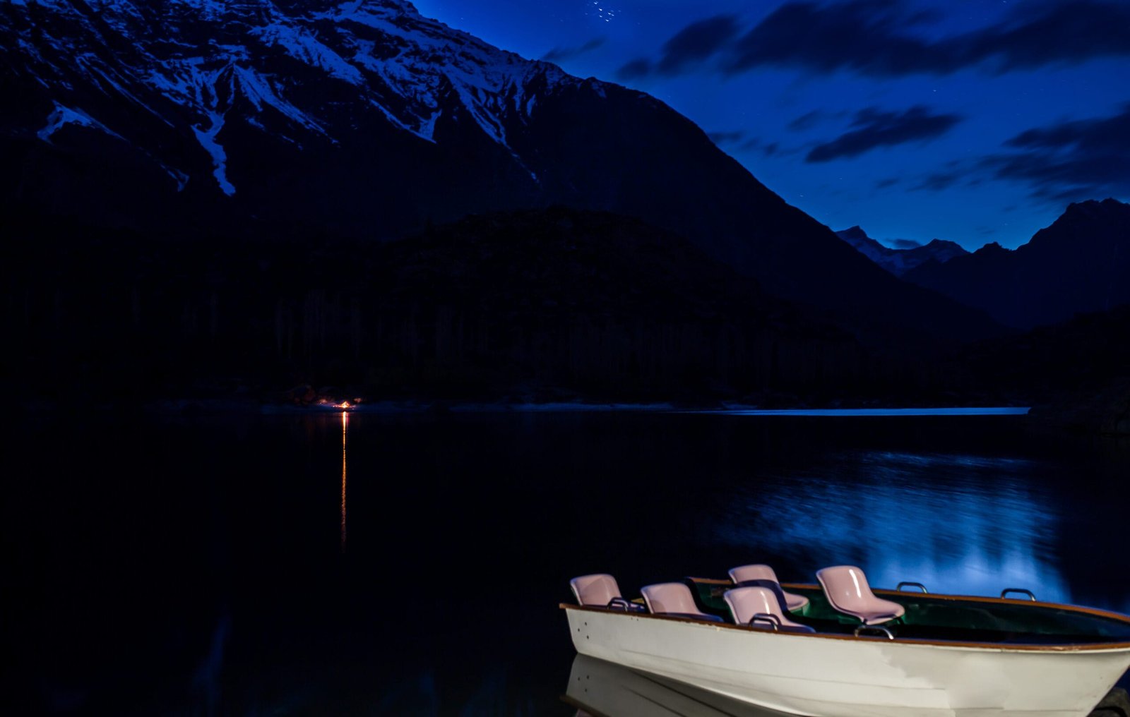 Upper Kachura Lake at dusk with a wooden rowing boat and mountains behind