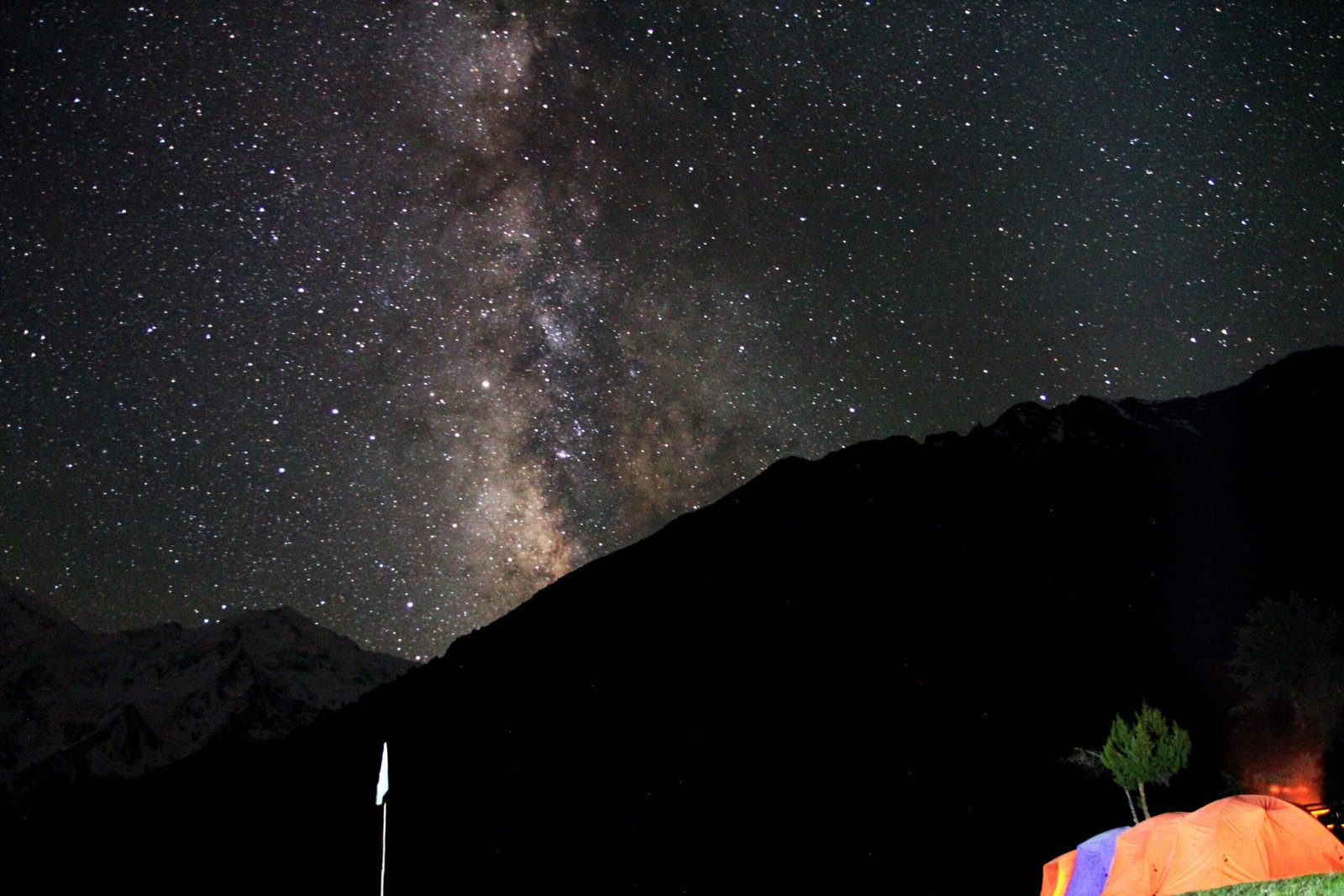 Milky way and stars over the wooden cottages and campsite at Fairy Meadows at night