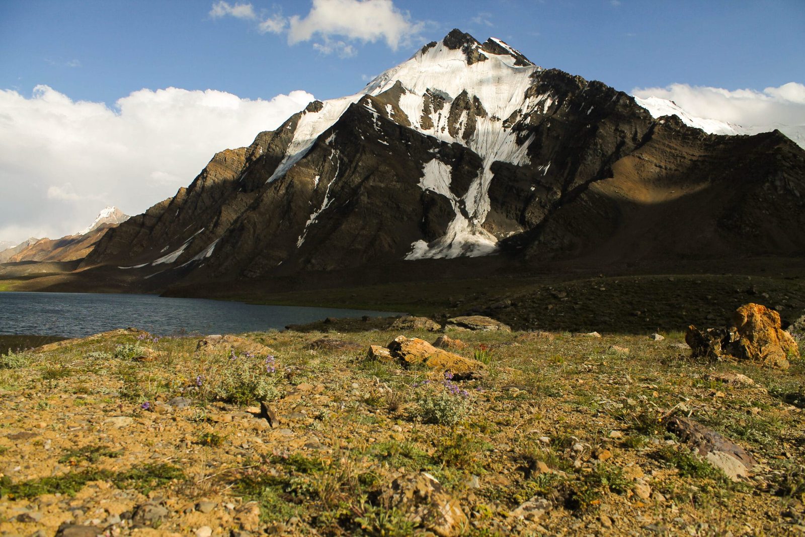 Karambar Lake seen from the Broghil side of the watershed, with high pasture and bare ridges around the water