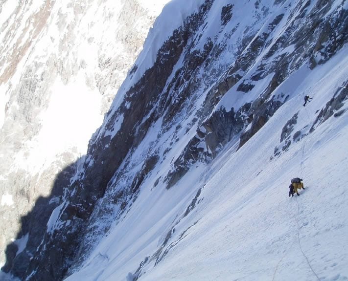 Bergsteiger quert ein Schneeband in der Südwestwand des Khunyang Chhish East