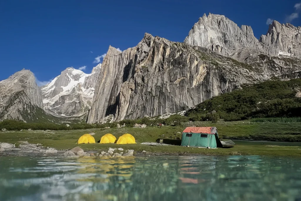 Expedition base camp tents beneath a granite wall in the Karakoram