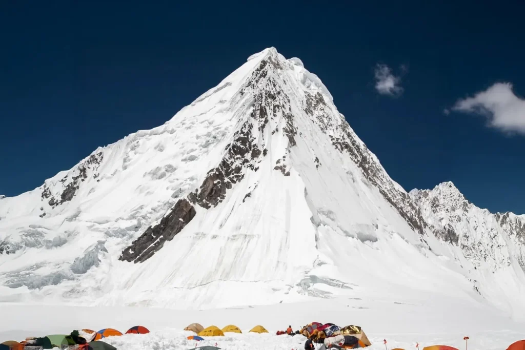 Expedition base camp on moraine below a pyramid-shaped peak