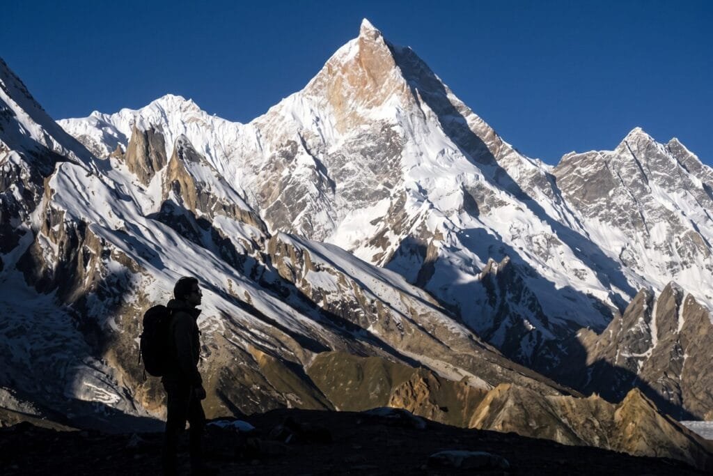 Trekker silhouetted against Masherbrum on the K2 Base Camp trek, Baltistan