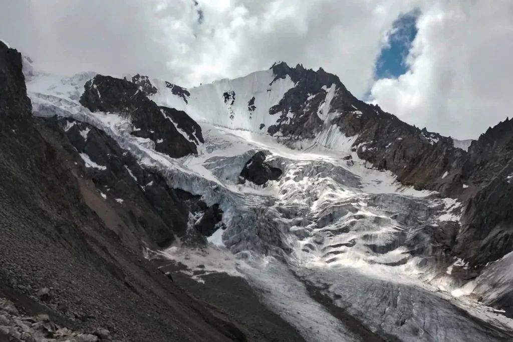 Moody light over a glacier and dark rock peaks
