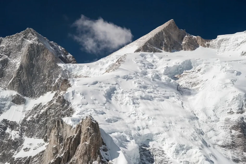 Snow peak with tiered ice cliffs under a deep blue sky