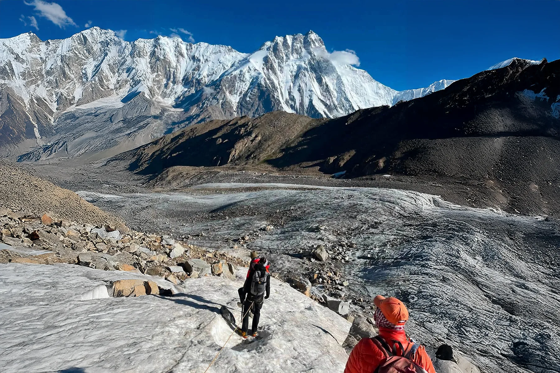 Cordée de trekkeurs sur un glacier, sous un sommet géant du Karakoram