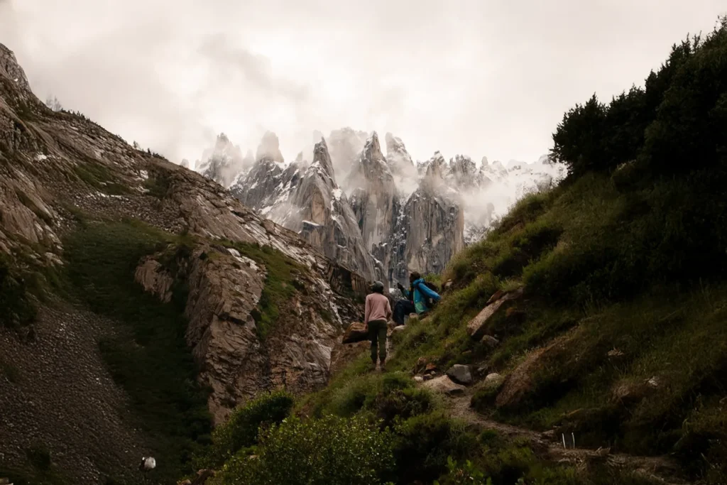 Trekkers on a green trail walking toward granite spires