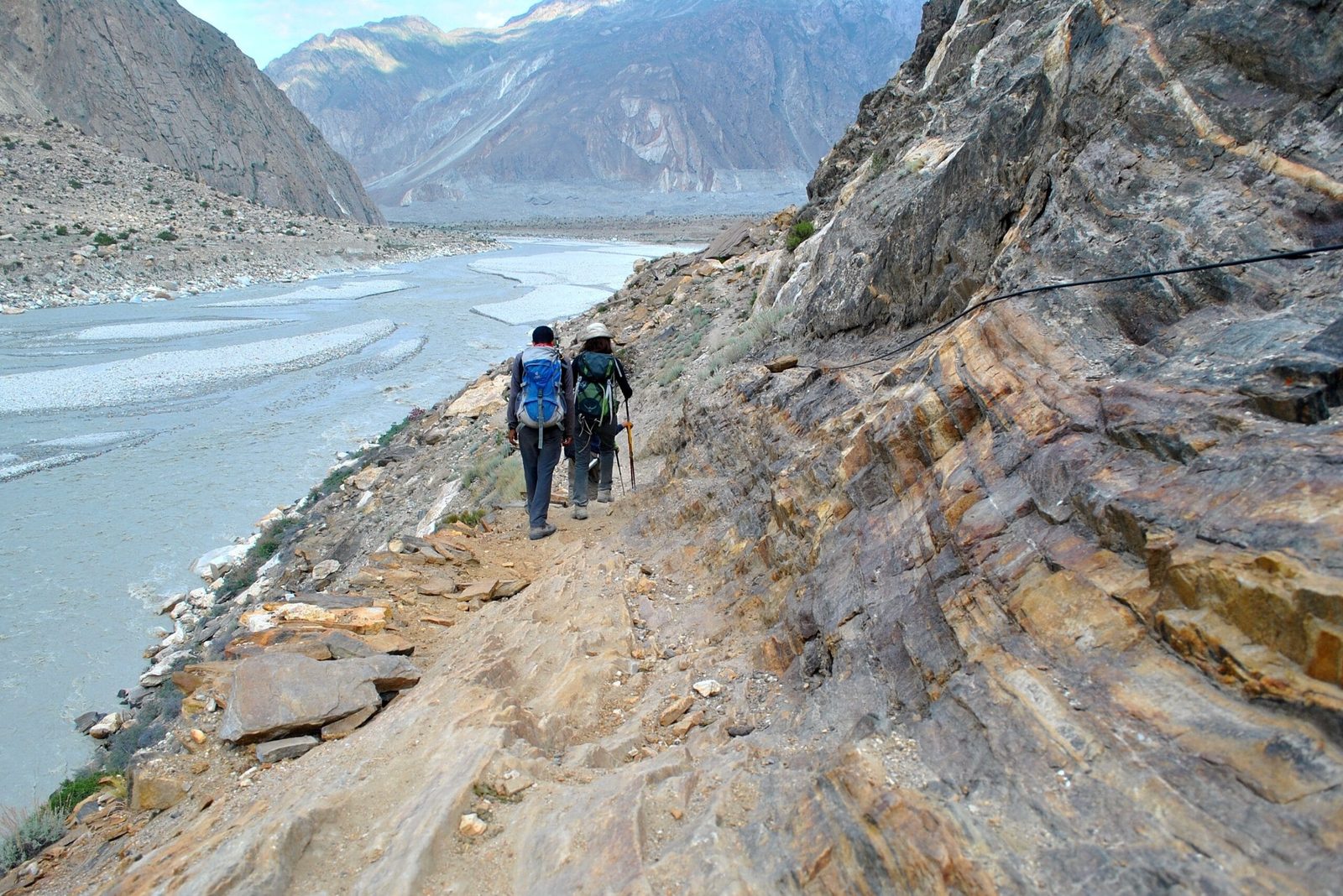 Trekkers trail along the dry Braldu valley between Jhola campsite and Askole