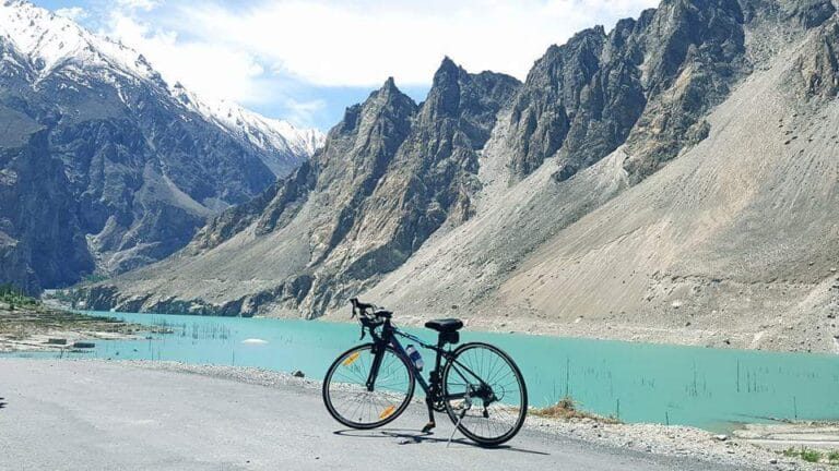 A road bike parked beside turquoise Attabad Lake on the Karakoram Highway, Hunza